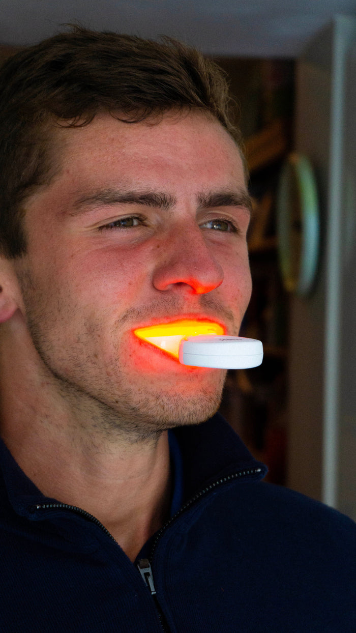Heliored oral device in use - dual light therapy mouthpiece against the gum line